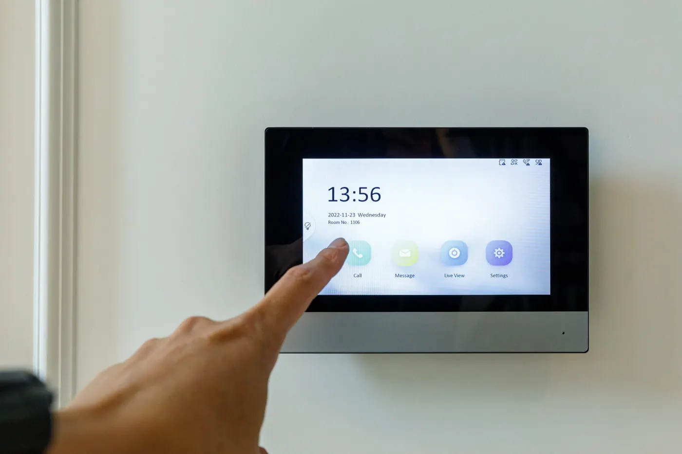 Indoor video intercom monitor on a wall, a finger touching the screen