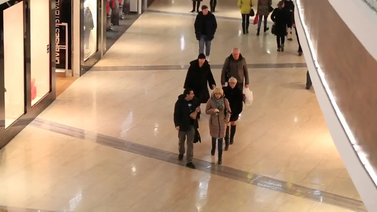 Shoppers walking through a mall concourse, seen from a high camera