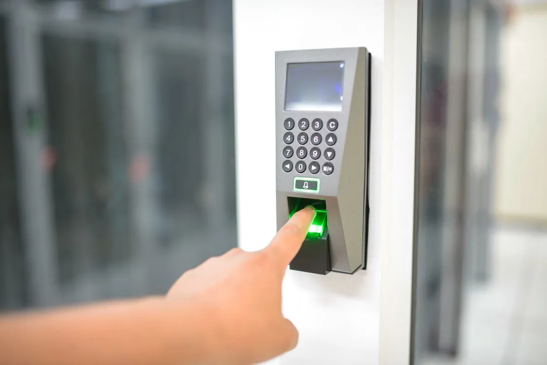 A finger on the green fingerprint sensor of a wall terminal