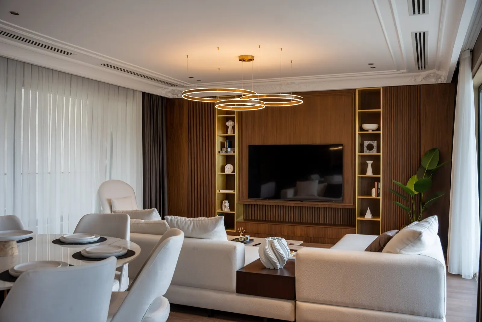 Modern villa living room with a TV wall, ring pendant lights and sheer curtains